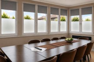 a conference room with a large wooden table and windows at HK-Vermietung - dezent, ordentlich und preiswert mit allem, was es wirklich braucht in Brieselang