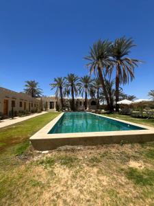 a swimming pool in a yard with palm trees at فندق إريغن Erighin siwa hotel in Siwa