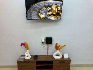 a desk with two vases and a picture on the wall at Palm & Tide Kenitra Residence in Kenitra