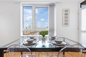 a dining room with a glass table with chairs and a window at Modern 2 Bed Flat 5 mins Ealing Broadway Station in Ealing