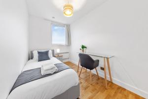 a bedroom with a bed and a desk and a chair at Modern 2 Bed Flat 5 mins Ealing Broadway Station in Ealing