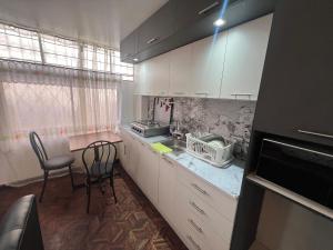 a kitchen with white cabinets and a table and chairs at Suite Acogedora Centro de Tulcán in Tulcán