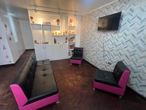 a living room with two chairs and a couch and a tv at Suite Acogedora Centro de Tulcán in Tulcán