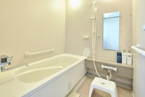 a white bathroom with a tub and a stool at Furano Lavender House helps guests book great restaurants in Furano in Furano +23 photos