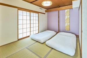 a room with two beds and two windows at Furano Lavender House helps guests book great restaurants in Furano in Furano