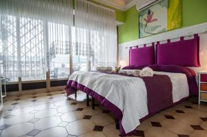 ローマにあるPasseggiate Romane B&Bのベッドルーム1室(紫色のベッドカバー付きの大型ベッド1台付)