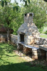 une cheminée en pierre avec un banc dans un parc dans l'établissement House Kisic, à Višnjan