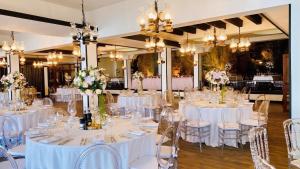 a banquet hall with white tables and chairs with flowers at Hotel Biser in Kališta