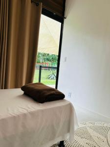 a pillow on a bed in a room with a window at Sítio Vivendas in Itaipava