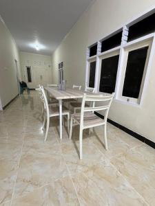 a white table and chairs in a room with windows at Homestay Whale Shark in Pohe