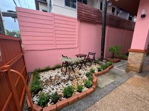 a pink wall with two chairs and a table in a garden at Aonang Poonsiri Cozy Villa in Ban Khlong Haeng