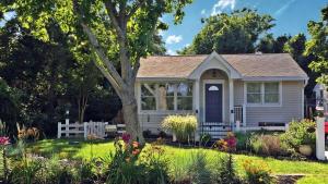 a small white house with a tree in the yard at Lakeview Retreat in Cape May Point