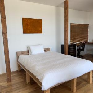 a bedroom with a white bed with a desk at Seaside Inn KOKOMO in Hakodate