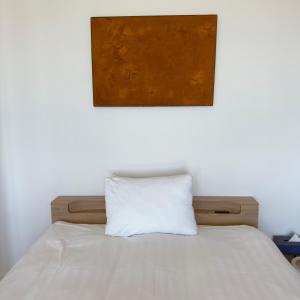 a bed with a white pillow under a painting at Seaside Inn KOKOMO in Hakodate