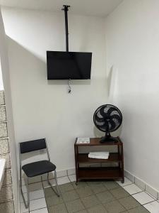 a room with a chair and a television on a wall at Pousada São Paulo - Quartos com WC Exclusivo in Recife +24 photos
