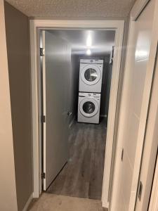 a washer and dryer in a room with a hallway at Cozy private basement suite with separate entrance in Calgary
