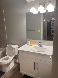 a bathroom with a toilet and a sink and a mirror at Cozy private basement suite with separate entrance in Calgary +4 photos