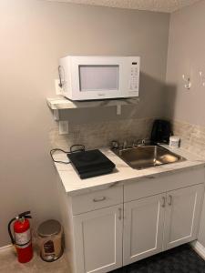 a kitchen with a sink and a microwave at Cozy private basement suite with separate entrance in Calgary