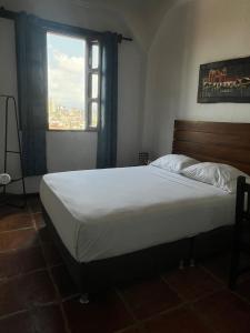 a bedroom with a large bed with a window at Hotel Terraza San Antonio in Cali