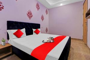 a bedroom with a bed with red and white pillows at Hotel O Fox Guest House in Greater Noida +18 photos