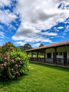 a building with a fence and some pink flowers at Looking Samaipata Habitación Doble in Samaipata