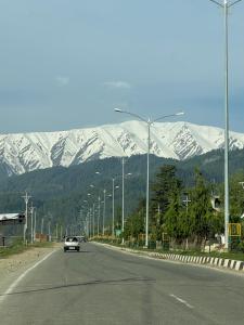a car driving down a road with snow covered mountains at Everest Guest House in Gulmarg +14 photos