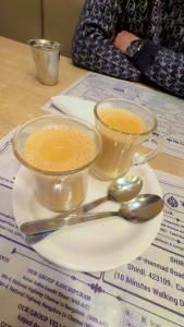 two cups of coffee sitting on a plate with spoons at Everest Guest House in Gulmarg
