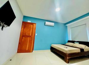 a bedroom with blue walls and a bed and a television at Hotel Zabdy in Liberia