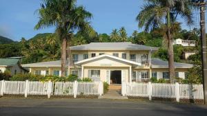a white fence in front of a house with palm trees at New Mavida Lodge in Levuka