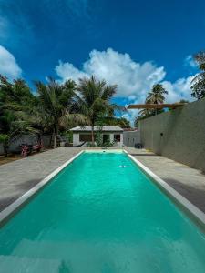 a swimming pool with blue water in front of a house at Rancho de férias in Japaratinga