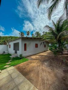 a white house with palm trees in front of it at Rancho de férias in Japaratinga