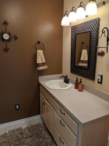a bathroom with a sink and a mirror at FIFA Basecamp with 2 Kitchens, 5BR, 4 Baths in Roeland Park +11 photos
