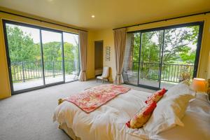 a bedroom with a large bed and large windows at Ballymoney Cnoc in Tai Tapu