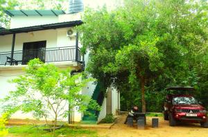 a car parked next to a house with a tree at The LeoEye Wilpattu in Pahala Maragahawewa