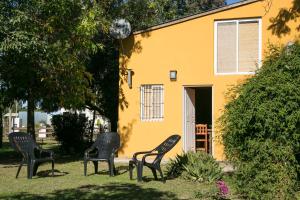 three chairs sitting in front of a yellow house at El Solar in Vuelta de Obligado