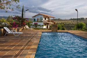 a villa with a swimming pool and a house at Cabañas Campestres El Vaticano in Barichara