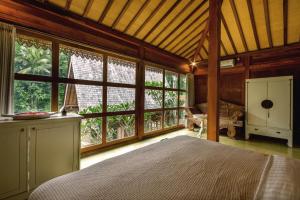 a bedroom with a bed in a room with windows at The Villa Lululu in Tabanan +76 photos