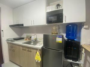 a small kitchen with a refrigerator and a sink at Staycation Hub in Mandaue City