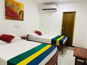two beds in a room with a painting on the wall at Ratnam Hotel Jaffna in Jaffna