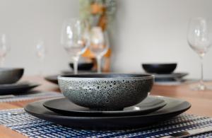 a table with black bowls and plates and wine glasses at Koblenz Haus - “Heart of the Barossa” - (New Mgmt) in Tanunda