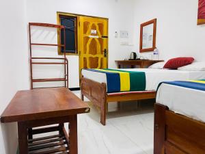 a bedroom with two beds and a table and a ladder at Ratnam Hotel Jaffna in Jaffna