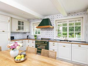 a kitchen with white cabinets and a table with a vase of flowers at Leuchtturmblick-Sued in Kampen