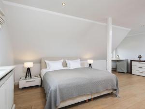 a white bedroom with a large bed and two lamps at Leuchtturmblick-Sued in Kampen