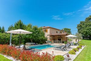 a pool with chairs and umbrellas in a yard at Family Villa Krizanci Istria in Žminj