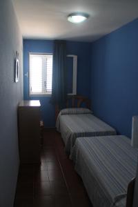 a blue room with two beds and a window at Apartamentos El Puerto in Alcossebre