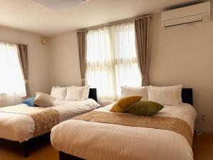 two beds in a hotel room with windows at Villa和心 in Asahikawa +55 photos
