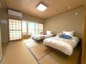 a bedroom with two beds in a room with windows at Villa和心 in Asahikawa