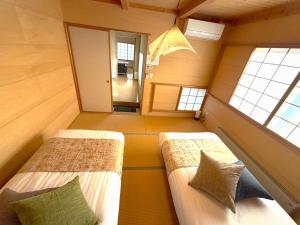 two beds in a small room with two windows at Villa和心 in Asahikawa