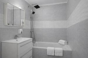 a bathroom with a tub and a sink and a mirror at Comfort 65 2-Bedroom Apartment with Balcony in Miskolc