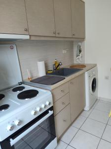 a kitchen with a stove and a sink and a washing machine at Manolia !!! in Kranidi